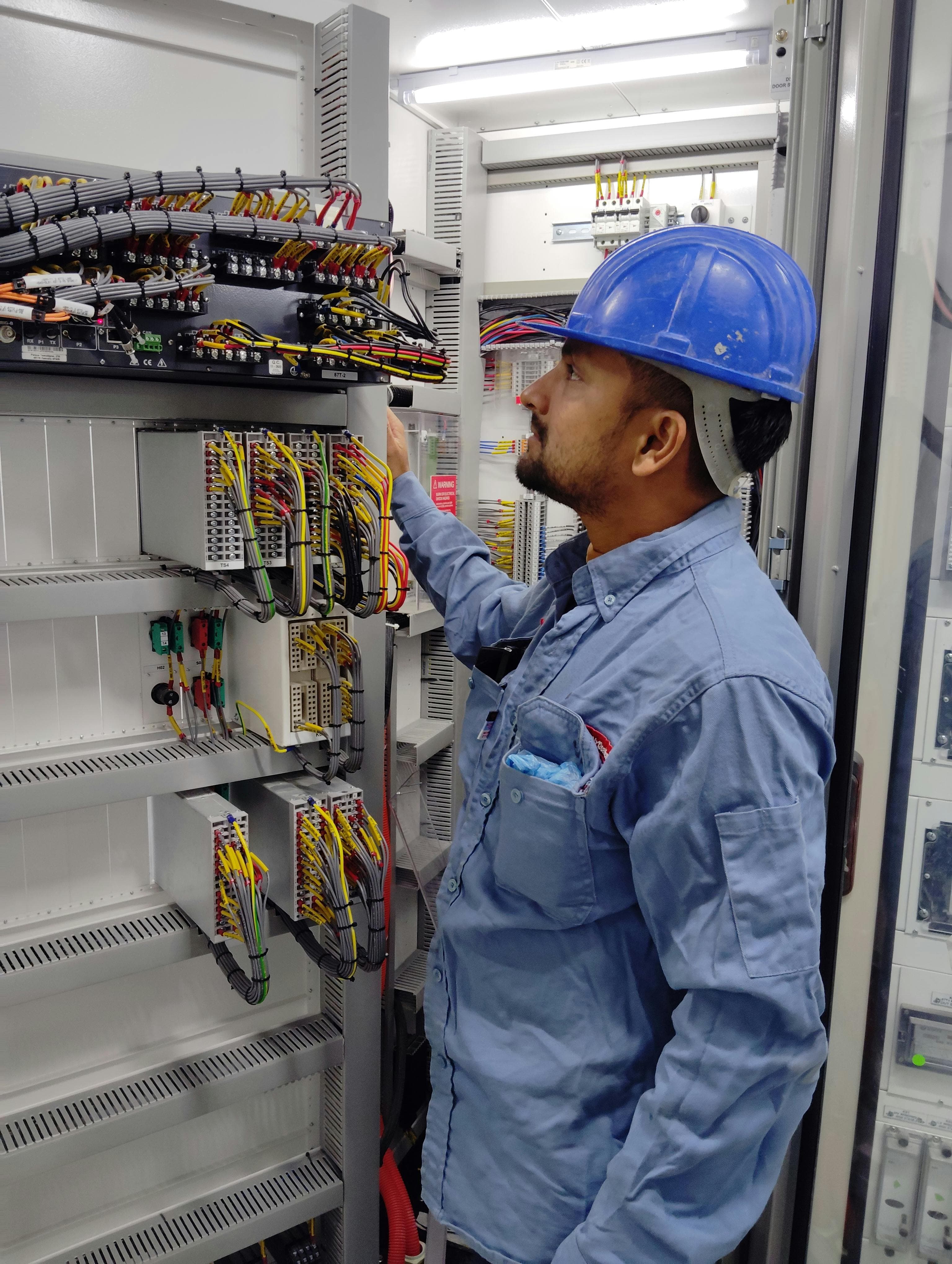 Controls engineer working inside an industrial control panel cabinet